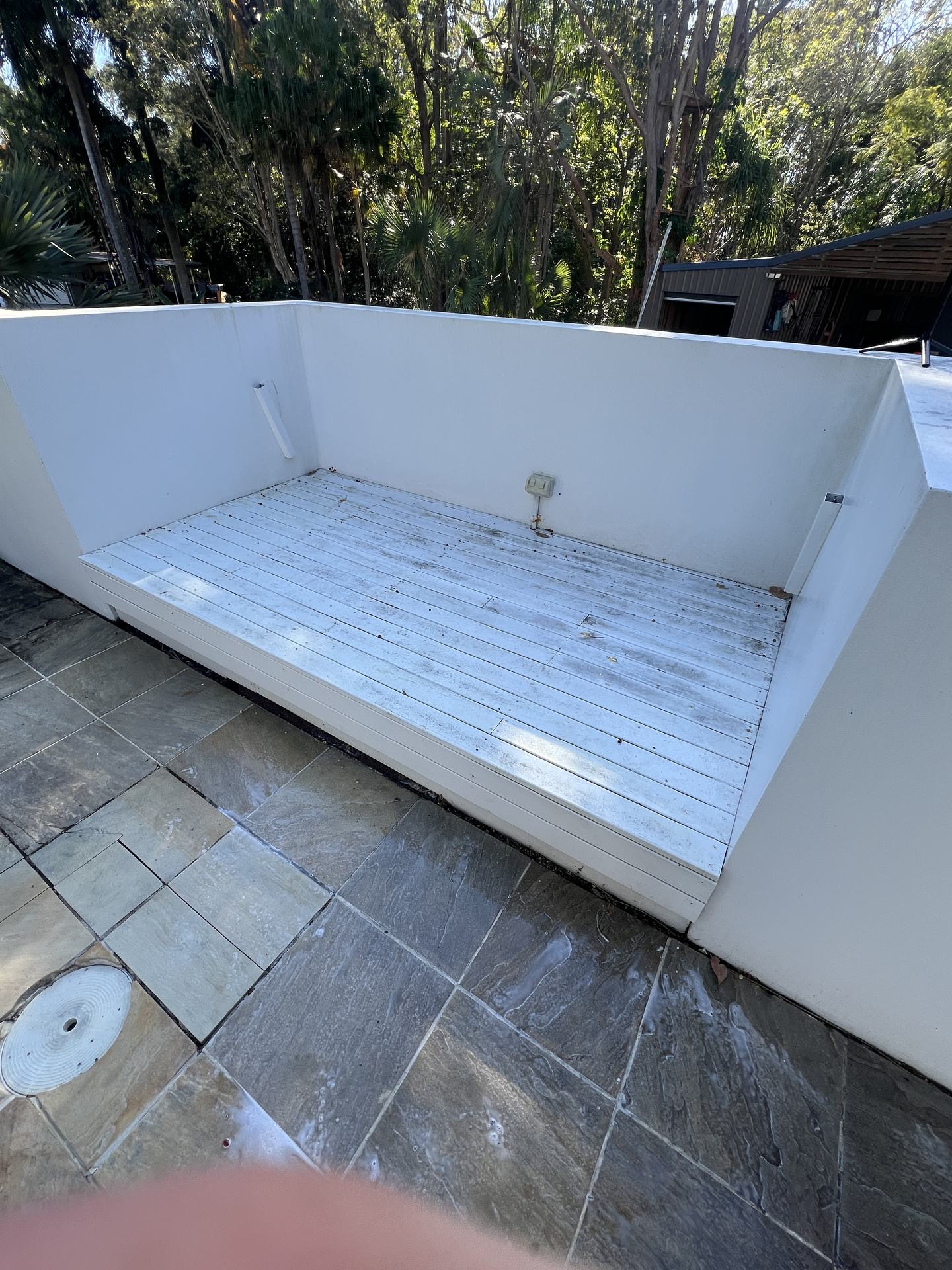 Painted timber daybed deck before cleaning, grey weathered grime across the boards